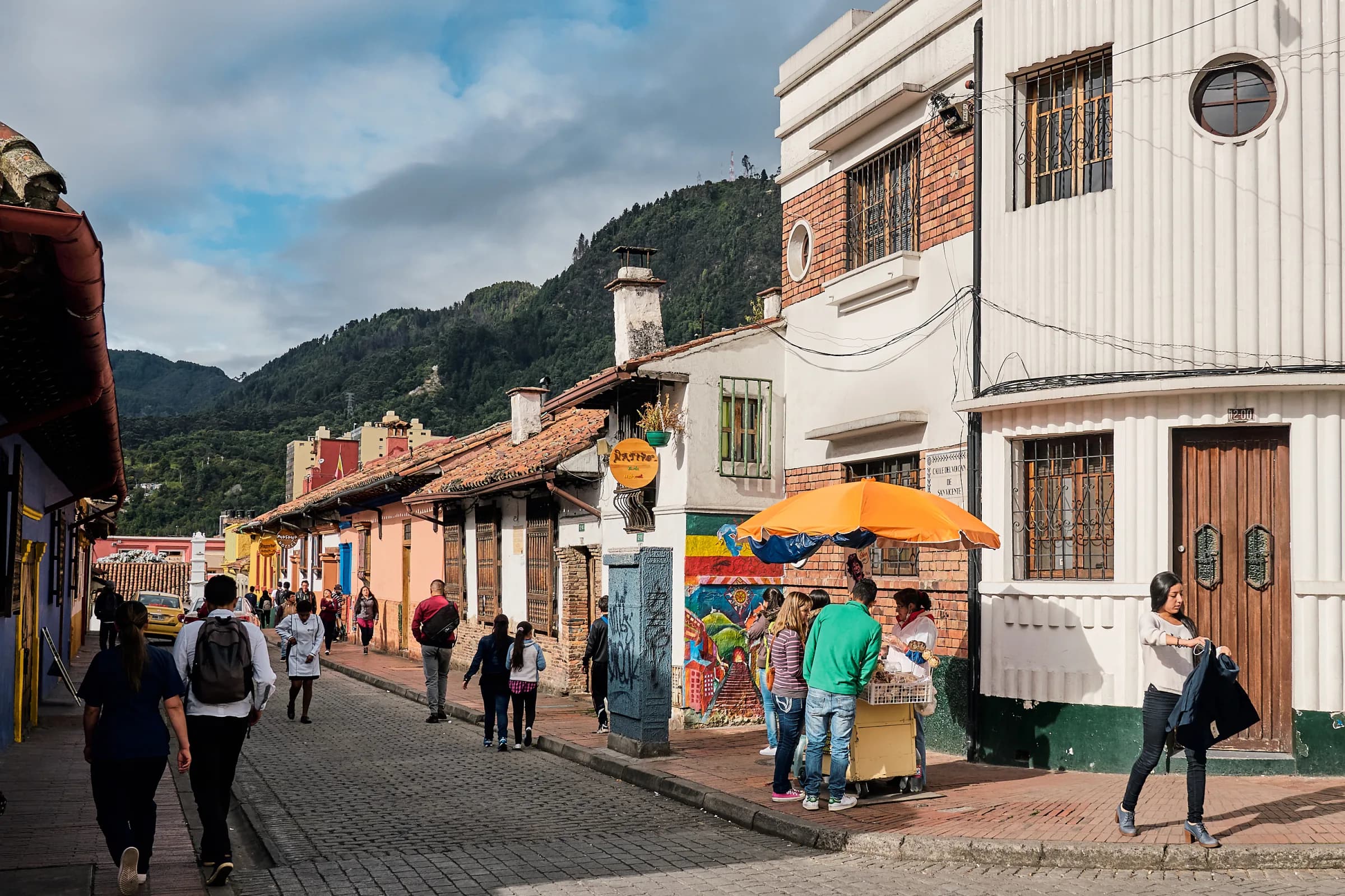 Rue colorée du quartier de La Candelaria avec les montagnes de Bogotá en arrière-plan.